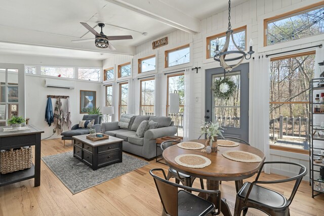 interior space with a wealth of natural light, light wood-type flooring, a wall mounted AC, and a ceiling fan