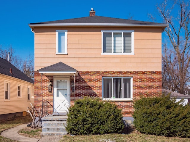 view of front of home with a chimney and brick siding