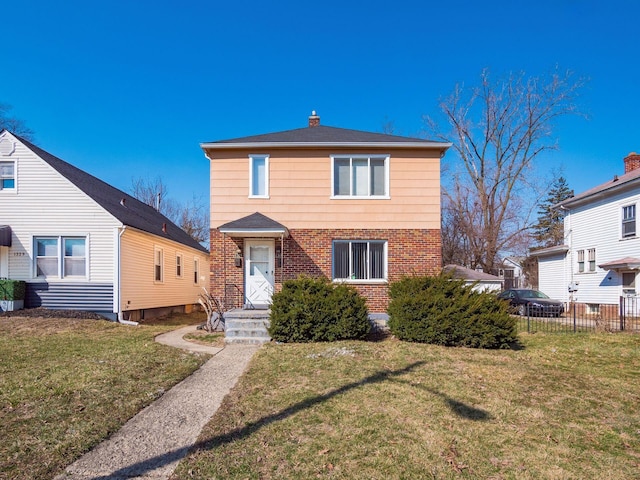 traditional-style home featuring brick siding, a front yard, and fence