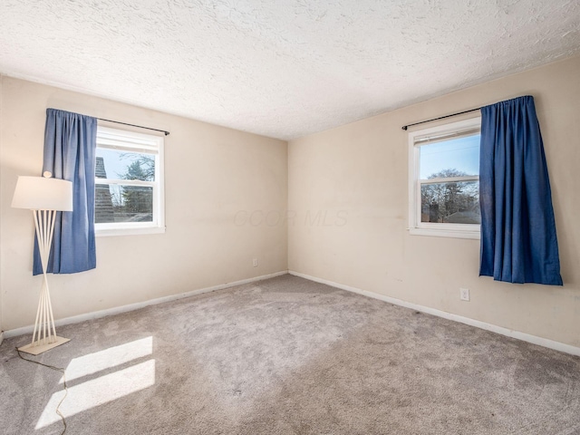 carpeted empty room featuring baseboards and a textured ceiling