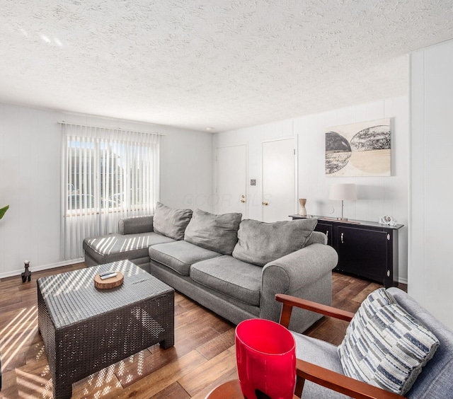 living area with a textured ceiling, baseboards, and wood finished floors