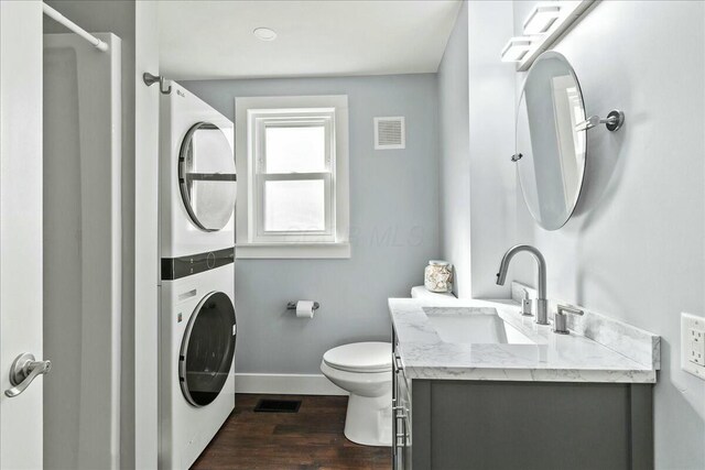 8119 State Route 366, Russells Point, OH 43348 - bathroom featuring toilet, baseboards, stacked washer and dryer, visible vents, and wood finished floors