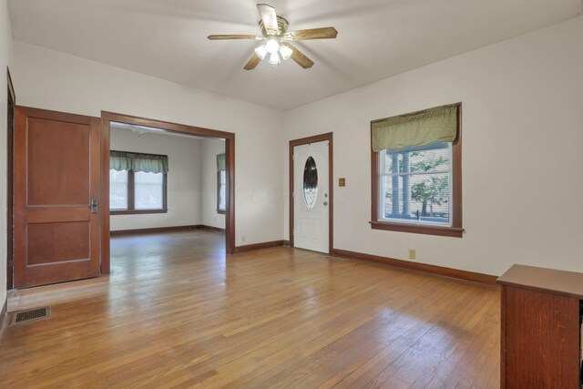 foyer entrance with light wood finished floors, baseboards, visible vents, and a ceiling fan