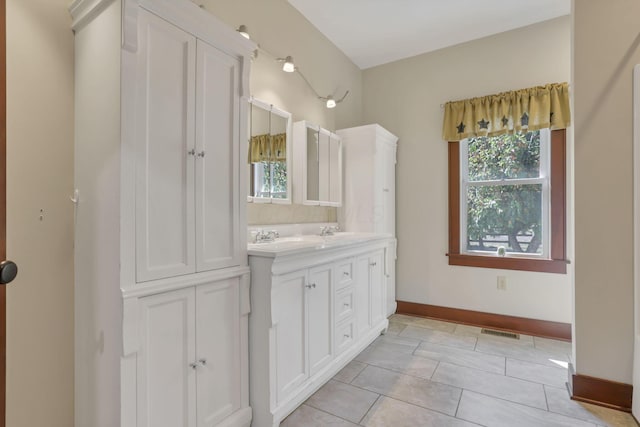 full bath featuring tile patterned flooring, baseboards, a sink, visible vents, and double vanity