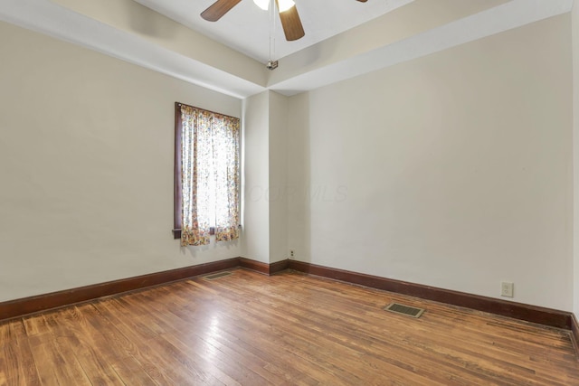 spare room with a ceiling fan, hardwood / wood-style flooring, baseboards, and visible vents