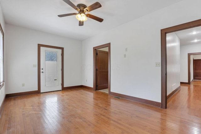 spare room with a ceiling fan, baseboards, light wood-style floors, and visible vents
