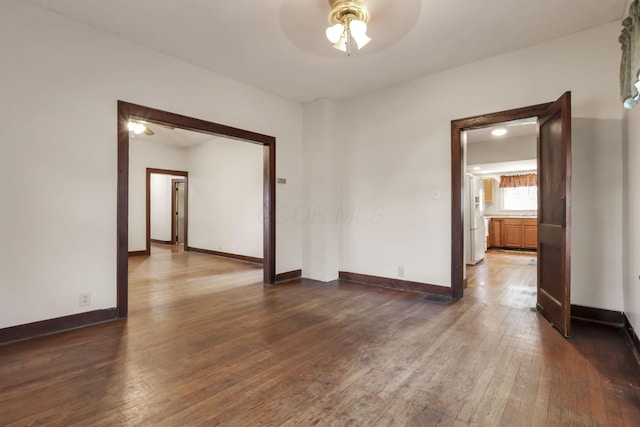 unfurnished room with dark wood-type flooring, ceiling fan, and baseboards