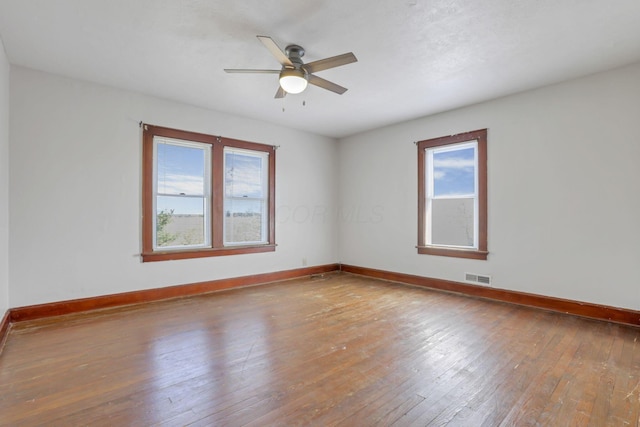 unfurnished room featuring hardwood / wood-style floors, baseboards, visible vents, and a ceiling fan