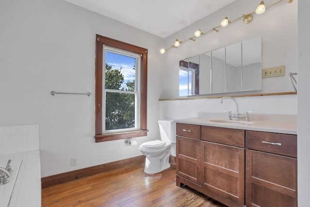 bathroom with toilet, wood finished floors, baseboards, and vanity