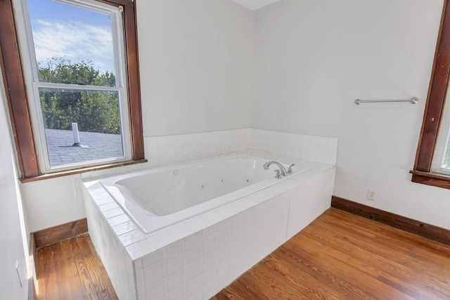 full bath featuring a tub with jets, baseboards, and wood finished floors
