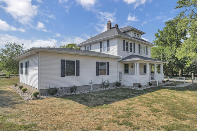 view of front of property featuring covered porch, a chimney, a shingled roof, and a front lawn