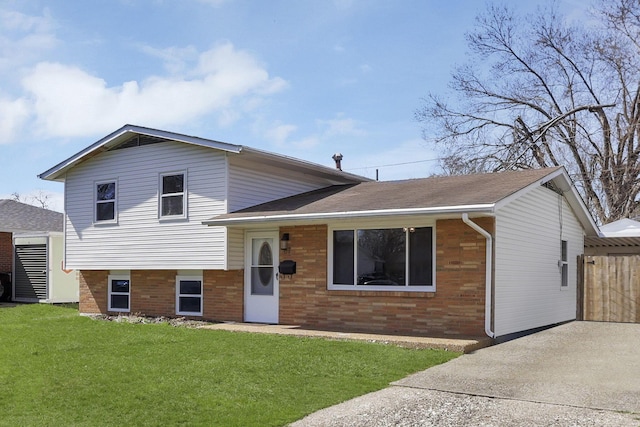 tri-level home with a front lawn, driveway, and brick siding