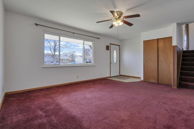 interior space featuring a ceiling fan, carpet floors, baseboards, and stairs