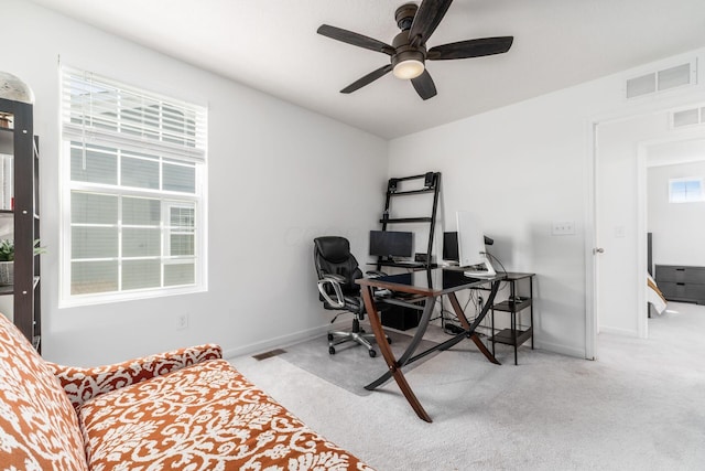 carpeted office space featuring baseboards, visible vents, and ceiling fan
