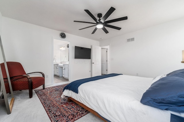 bedroom featuring ceiling fan, ensuite bath, light colored carpet, and visible vents