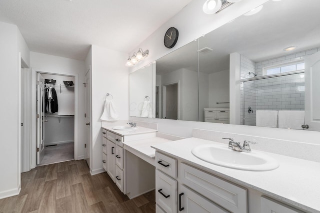 full bathroom with visible vents, wood finished floors, vanity, a stall shower, and a spacious closet