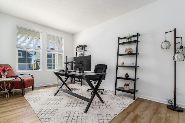 office area featuring baseboards, light wood finished floors, and visible vents