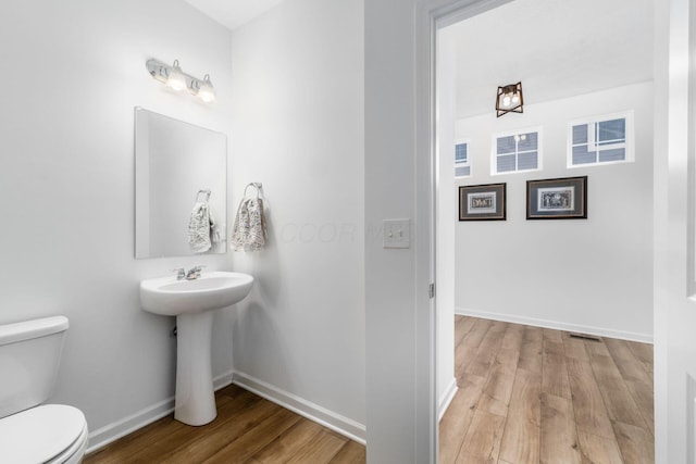 bathroom with baseboards, visible vents, toilet, and wood finished floors