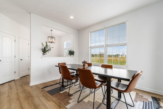 dining space featuring baseboards, light wood-style floors, a chandelier, and recessed lighting