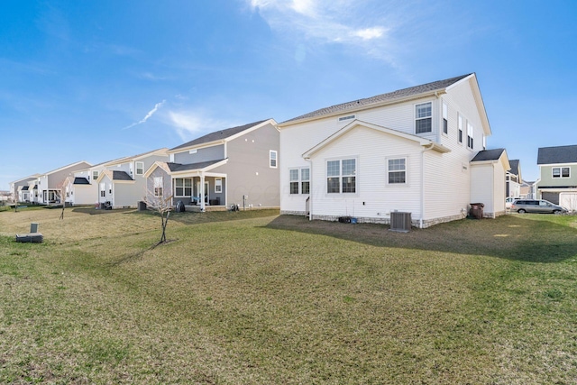 back of property with a residential view, central AC unit, and a lawn