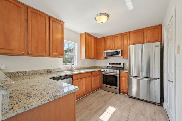 1143 Green Knoll Dr, Westerville, OH 43081 - kitchen featuring a sink, light stone counters, brown cabinetry, and appliances with stainless steel finishes