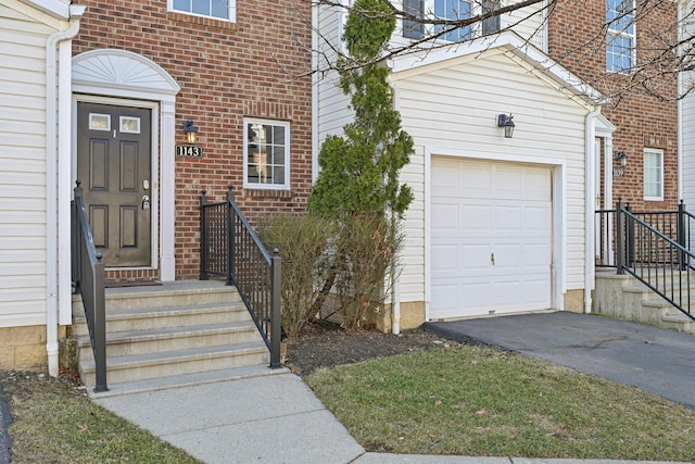 1143 Green Knoll Dr, Westerville, OH 43081 - view of exterior entry with brick siding, a garage, and aphalt driveway