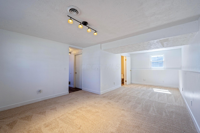 empty room with baseboards, carpet floors, a textured ceiling, and visible vents