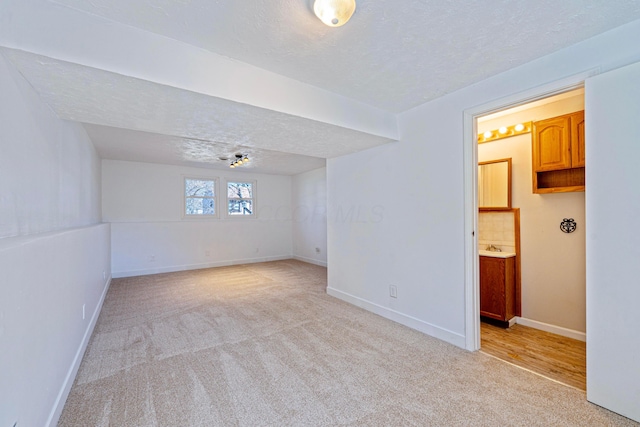 empty room with baseboards, light colored carpet, and a textured ceiling