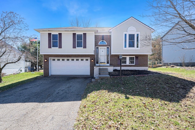 split foyer home with driveway, brick siding, an attached garage, and a front yard