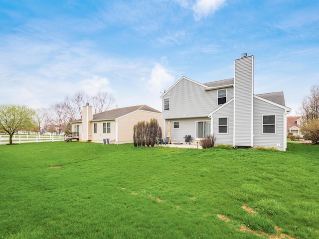 rear view of property featuring a patio, a yard, fence, and a chimney