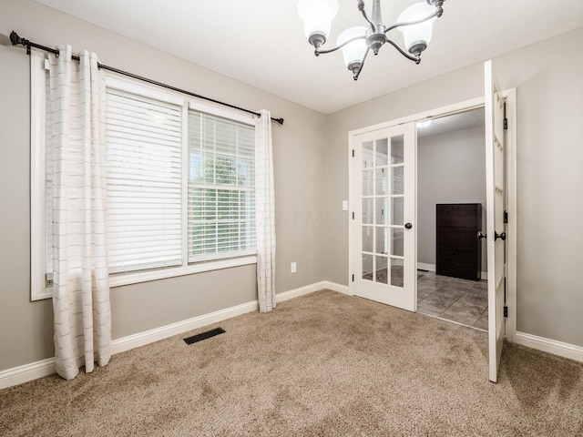 unfurnished room with visible vents, baseboards, a notable chandelier, carpet, and french doors