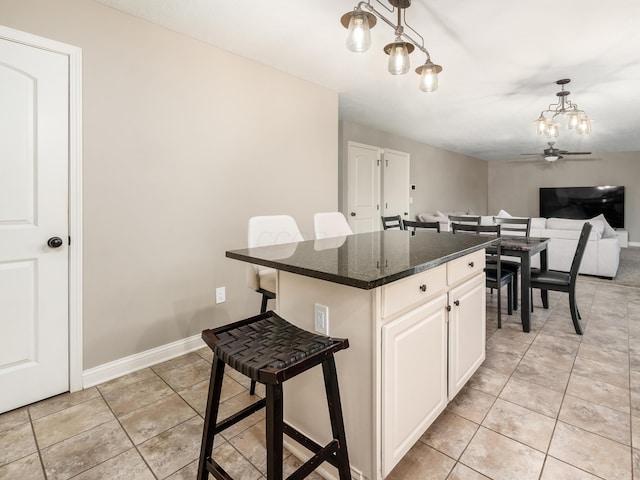kitchen featuring light tile patterned floors, a center island, baseboards, decorative light fixtures, and a breakfast bar area