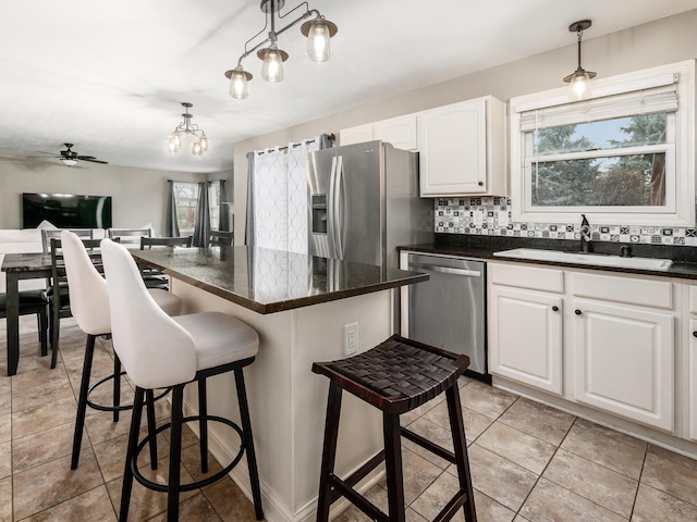 kitchen featuring backsplash, white cabinets, a breakfast bar area, appliances with stainless steel finishes, and a sink