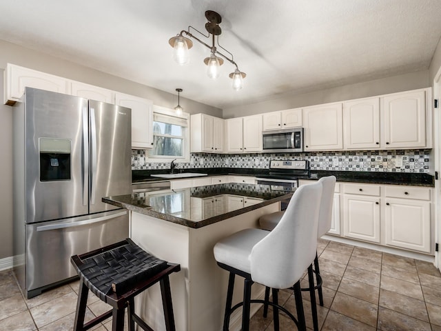 kitchen featuring appliances with stainless steel finishes, decorative backsplash, a sink, and white cabinetry