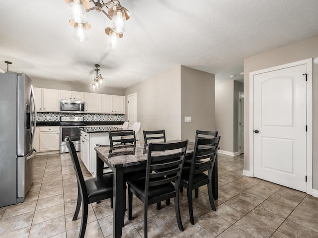 dining room with light tile patterned floors, a notable chandelier, and baseboards