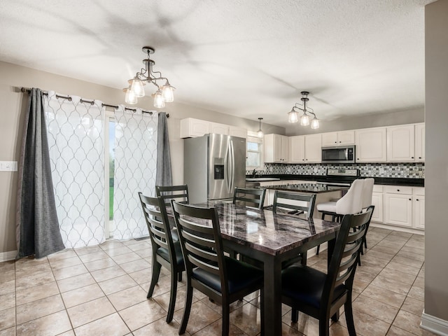 dining space featuring a textured ceiling, an inviting chandelier, and light tile patterned flooring