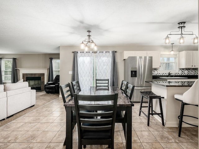 dining room featuring a chandelier, a fireplace, and light tile patterned flooring