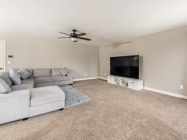 carpeted living area with ceiling fan and baseboards