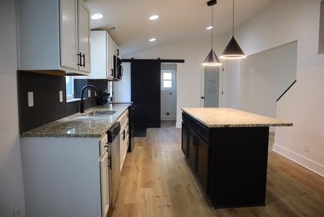 16786 Main St, Williamsport, OH 43164 - kitchen featuring light wood-style flooring, a barn door, appliances with stainless steel finishes, light stone counters, and lofted ceiling