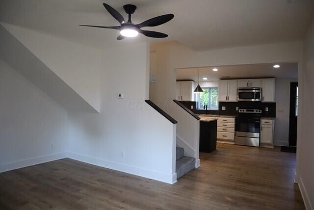16786 Main St, Williamsport, OH 43164 - kitchen with appliances with stainless steel finishes, dark wood-type flooring, white cabinets, a ceiling fan, and pendant lighting