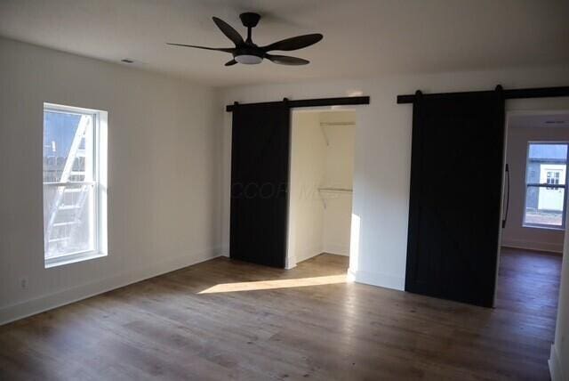 16786 Main St, Williamsport, OH 43164 - unfurnished bedroom featuring a barn door, wood finished floors, a closet, and a ceiling fan