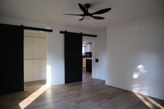 16786 Main St, Williamsport, OH 43164 - unfurnished bedroom featuring a barn door, wood finished floors, a spacious closet, and a closet