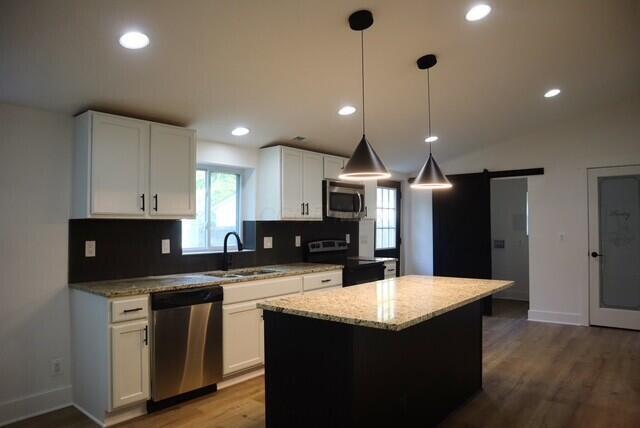 16786 Main St, Williamsport, OH 43164 - kitchen with stainless steel appliances, wood finished floors, light stone countertops, white cabinetry, and a kitchen island