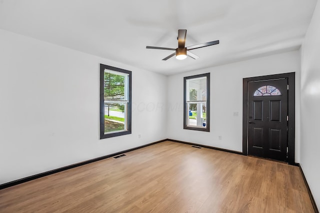 foyer entrance with baseboards, light wood finished floors, ceiling fan, and visible vents