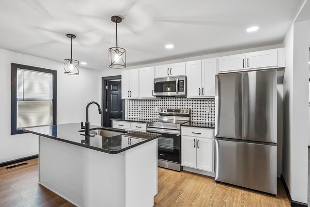 kitchen with tasteful backsplash, visible vents, a sink, appliances with stainless steel finishes, and light wood finished floors
