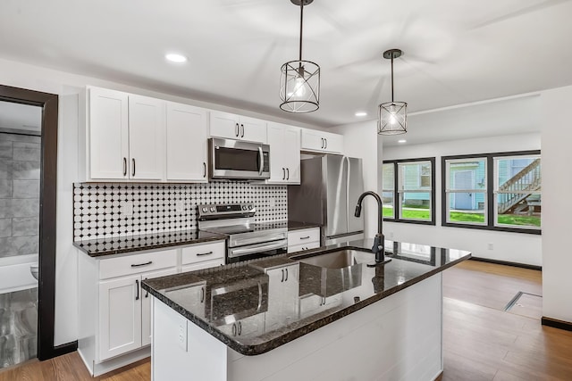 kitchen featuring light wood-style flooring, white cabinetry, a sink, stainless steel appliances, and decorative backsplash