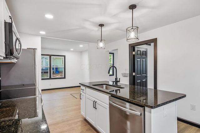 kitchen with decorative light fixtures, a sink, light wood-type flooring, appliances with stainless steel finishes, and white cabinetry