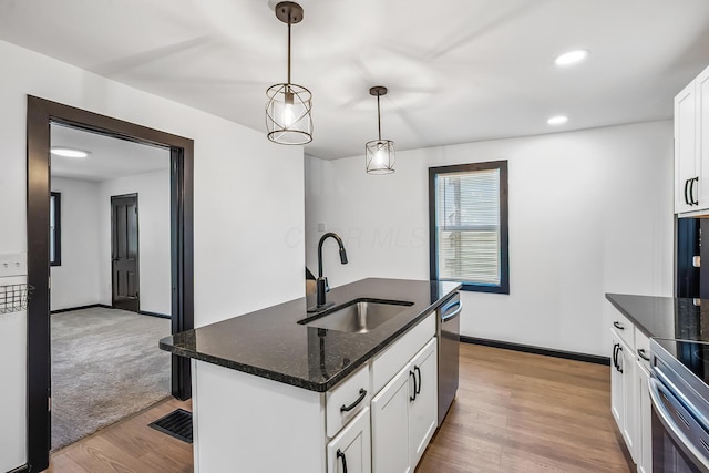kitchen featuring light wood-style floors, pendant lighting, white cabinets, a sink, and stainless steel appliances