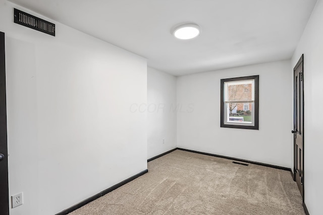 carpeted spare room featuring baseboards and visible vents