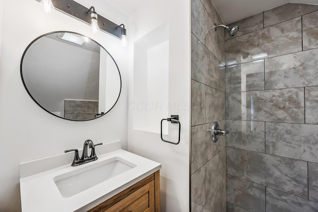 bathroom with a tile shower and vanity